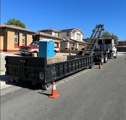 Park N Dump 10 yard lowboy dumpster on a residential street, with the roll-off truck behind it