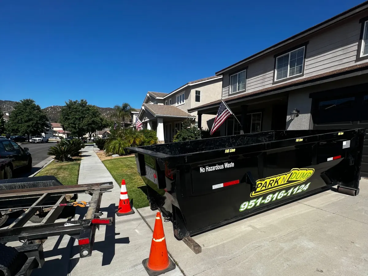 Park N Dump 15 yard dumpster on the driveway of a home, with cones beside it